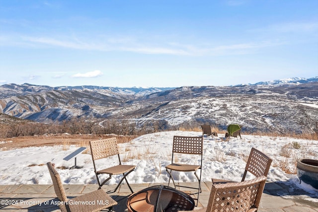 snow covered patio with a fire pit and a mountain view