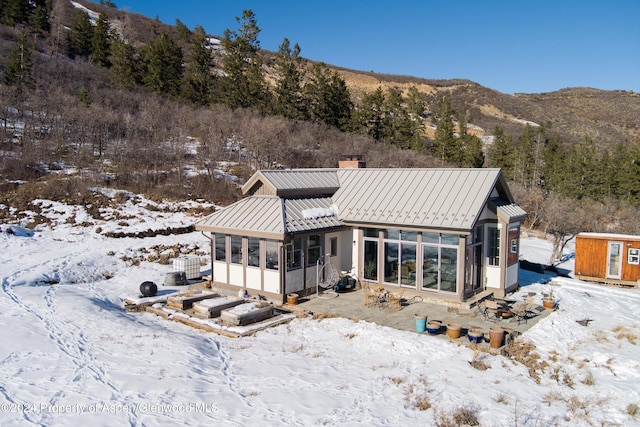 snow covered back of property featuring a mountain view