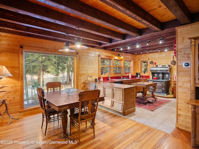 dining area with wood ceiling, wood walls, beamed ceiling, and light wood-style flooring