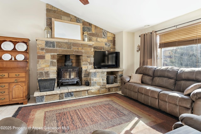 tiled living room with a wood stove, a ceiling fan, and vaulted ceiling