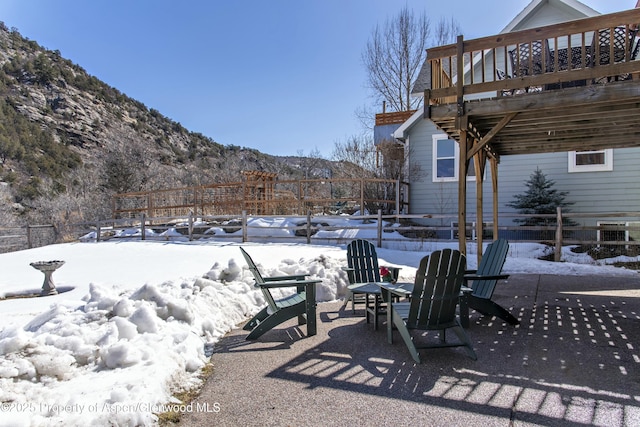 yard layered in snow with a patio and a deck with mountain view