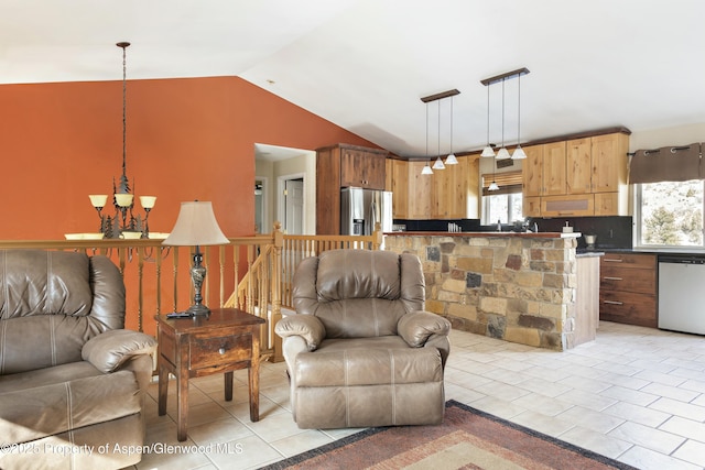 kitchen with lofted ceiling, hanging light fixtures, appliances with stainless steel finishes, dark countertops, and open floor plan