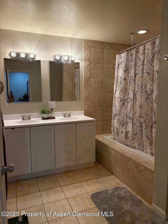 full bath with tile patterned flooring, tiled shower / bath combo, double vanity, and a sink