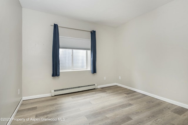 unfurnished room with a baseboard heating unit, baseboards, and wood finished floors