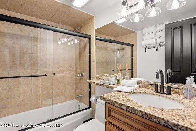 bathroom featuring enclosed tub / shower combo, toilet, and vanity
