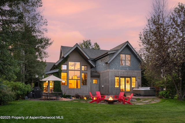 1185 Heritage Dr, Carbondale, CO 81623 - back of property at dusk with a hot tub, an outdoor fire pit, a patio area, and a yard