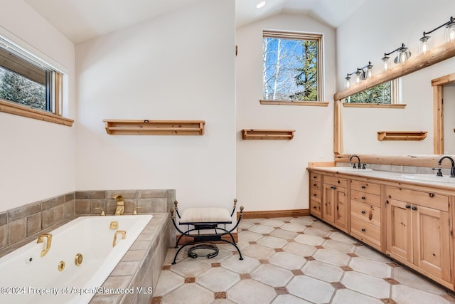 bathroom featuring vanity, tiled bath, and vaulted ceiling