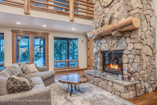 living room featuring wood-type flooring, a fireplace, and a high ceiling