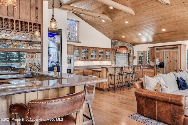 kitchen featuring beamed ceiling, a kitchen breakfast bar, wood ceiling, and high vaulted ceiling