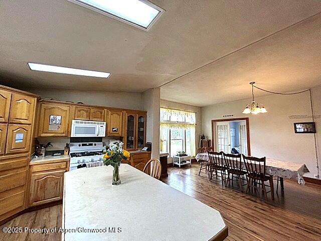 4050 County Road 7, Craig, CO 81625 - kitchen with white appliances, light countertops, dark wood finished floors, a chandelier, and brown cabinetry