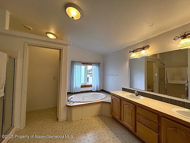 4050 County Road 7, Craig, CO 81625 - full bath featuring vaulted ceiling, a shower stall, tile patterned floors, a garden tub, and double vanity
