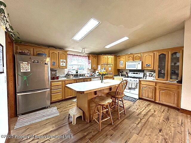 4050 County Road 7, Craig, CO 81625 - kitchen featuring white appliances, light wood-type flooring, light countertops, a breakfast bar, and a kitchen island