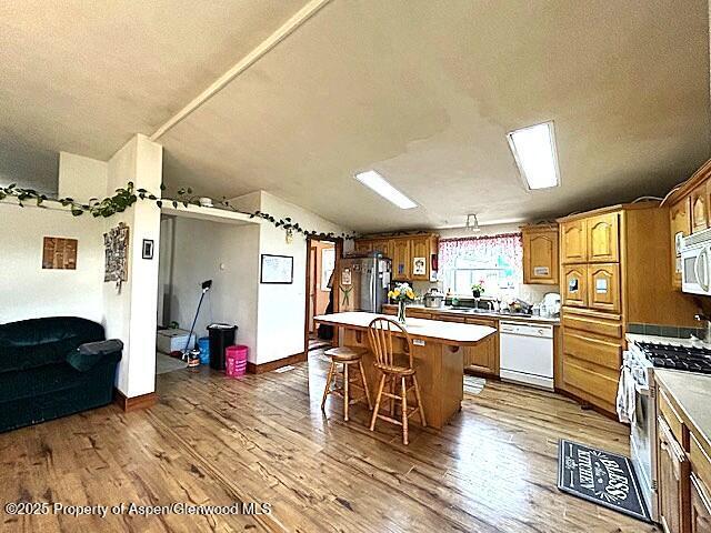 4050 County Road 7, Craig, CO 81625 - kitchen with appliances with stainless steel finishes, wood finished floors, a kitchen bar, a kitchen island, and light countertops
