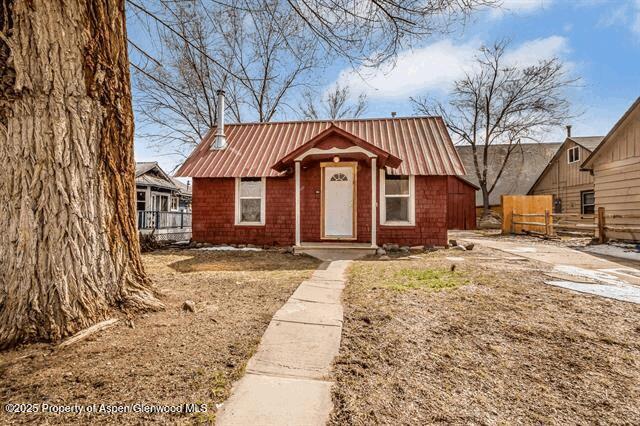 bungalow-style home with fence and metal roof