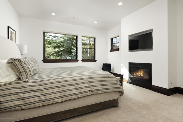 bedroom featuring baseboards, carpet floors, a glass covered fireplace, and recessed lighting