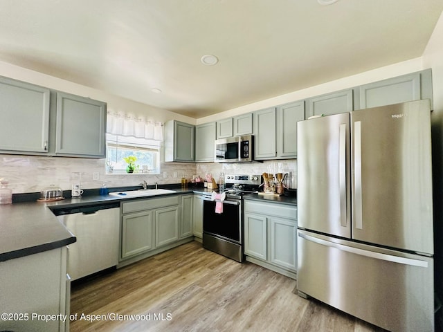 2529 Meadow Cir, Rifle, CO 81650 - kitchen featuring appliances with stainless steel finishes, dark countertops, decorative backsplash, light wood-style flooring, and recessed lighting