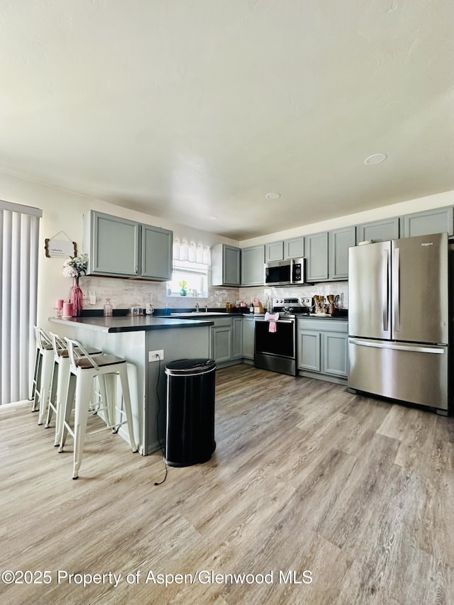 2529 Meadow Cir, Rifle, CO 81650 - kitchen with appliances with stainless steel finishes, dark countertops, light wood finished floors, and a peninsula