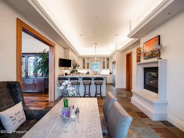 dining room featuring a raised ceiling, a wealth of natural light, and crown molding