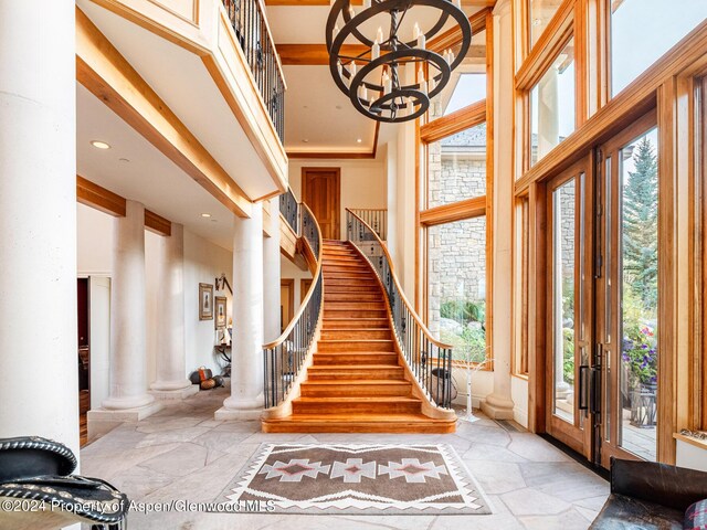 foyer entrance with decorative columns, a chandelier, and a high ceiling