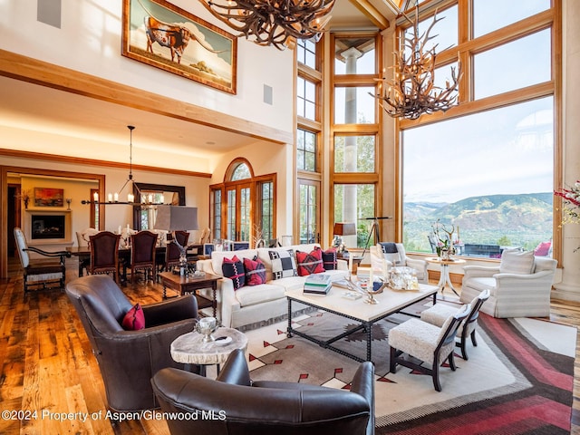 living room featuring hardwood / wood-style flooring, a mountain view, a towering ceiling, and a chandelier