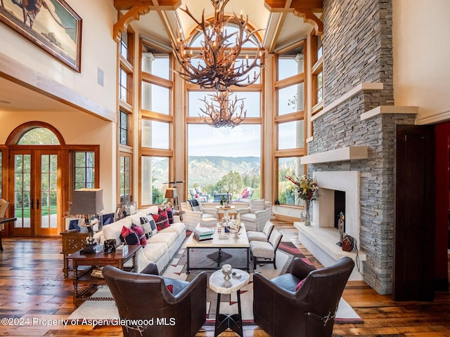 living room featuring a stone fireplace, a mountain view, french doors, and a towering ceiling