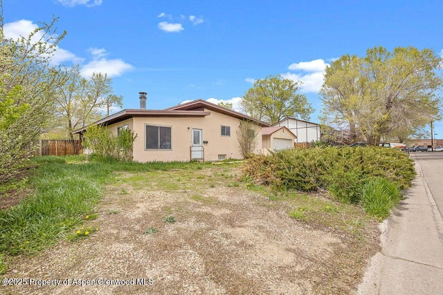 view of home's exterior featuring fence, stucco siding, and a garage