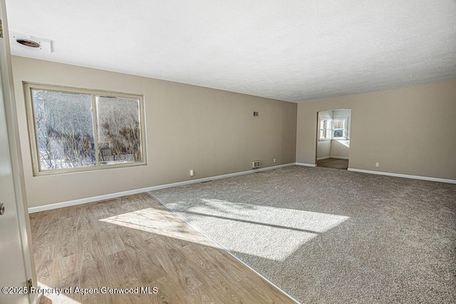 spare room featuring a textured ceiling and light hardwood / wood-style floors