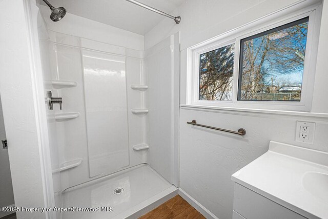 full bathroom featuring a stall shower, baseboards, wood finished floors, and vanity