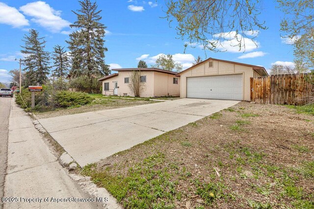 view of front of home featuring fence, a garage, concrete driveway, and stucco siding