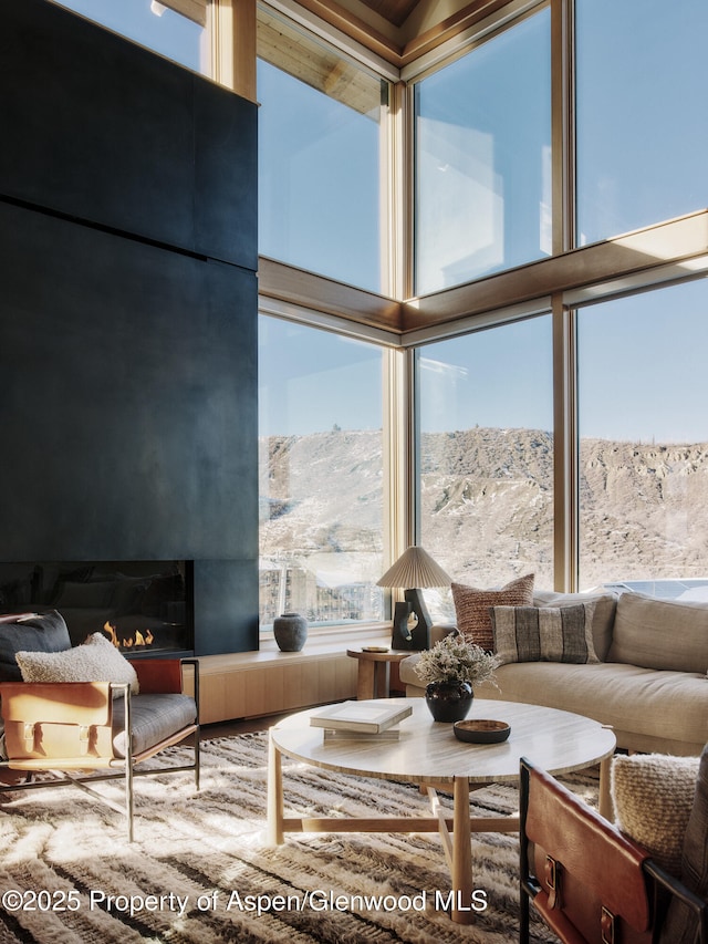 living area with a lit fireplace, a high ceiling, and a mountain view