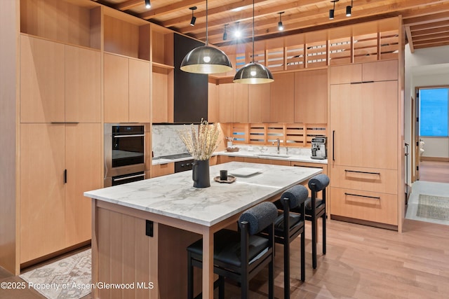 kitchen with modern cabinets, a sink, wooden ceiling, a kitchen island, and light wood-style flooring