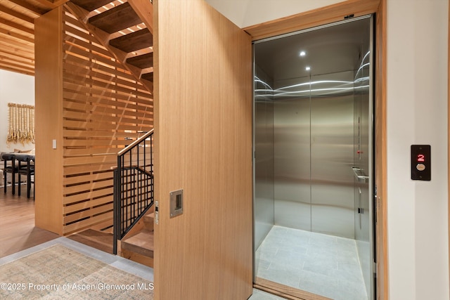 walk in closet featuring elevator and wood finished floors
