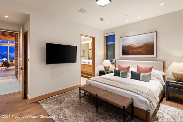 bedroom with light wood-style flooring, baseboards, recessed lighting, and ensuite bath
