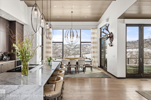 dining space with light hardwood / wood-style floors, wood ceiling, and a mountain view