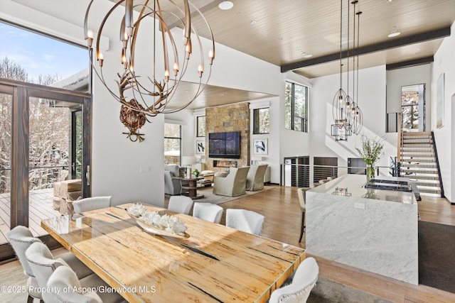 dining space featuring light wood-type flooring, beamed ceiling, and a notable chandelier