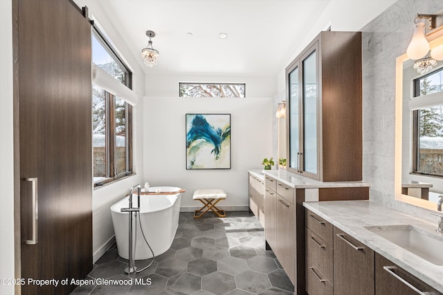 bathroom featuring a bathing tub, vanity, and a healthy amount of sunlight