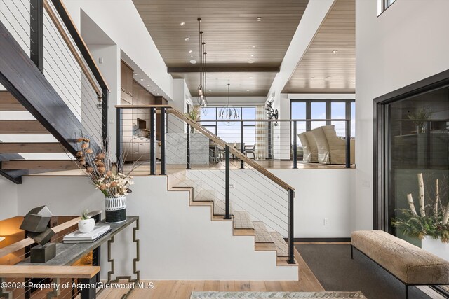 staircase featuring a towering ceiling, beamed ceiling, and wooden ceiling