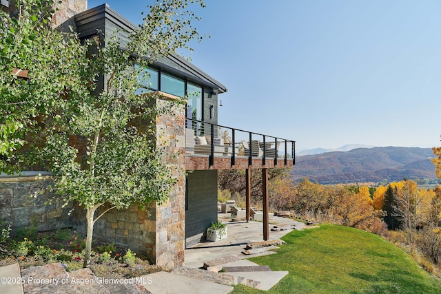 exterior space with a balcony, a lawn, and a mountain view