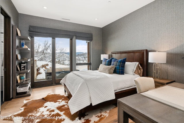 bedroom featuring a mountain view, light wood-type flooring, and access to exterior