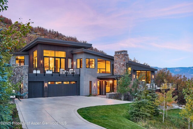 contemporary home featuring a mountain view, a garage, and a lawn