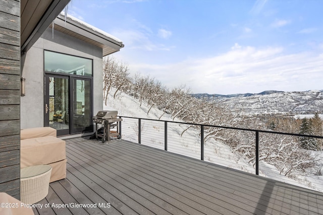 snow covered deck featuring area for grilling and a mountain view