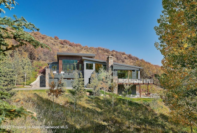 rear view of house with a sunroom and a deck with mountain view