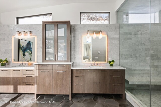 bathroom with a healthy amount of sunlight, tiled shower, and vanity