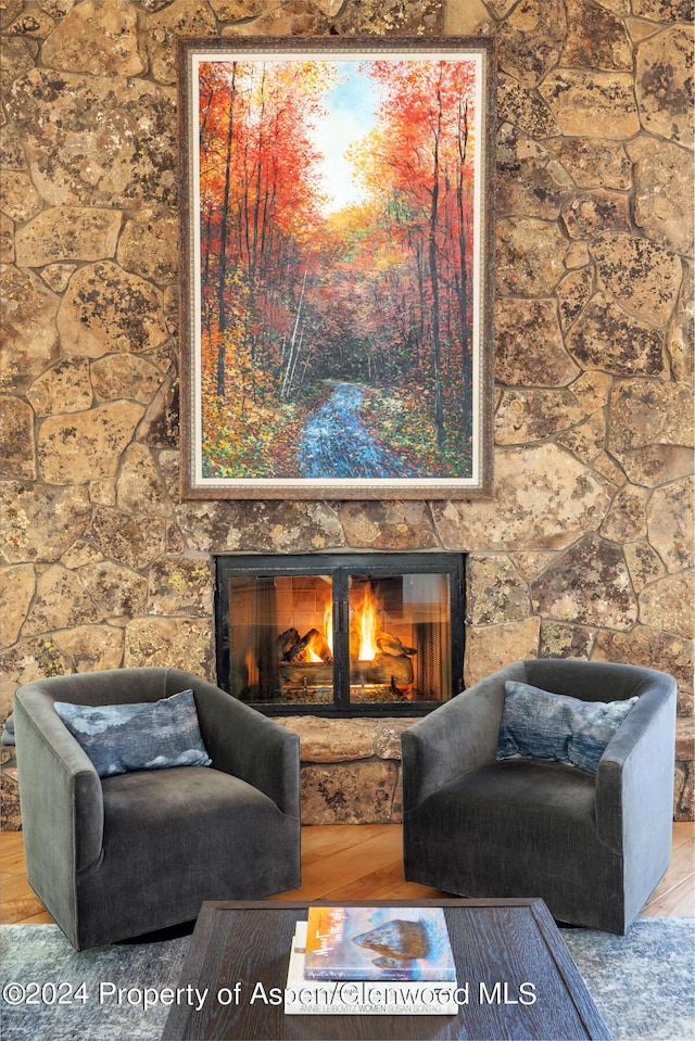 living area featuring hardwood / wood-style flooring and a stone fireplace