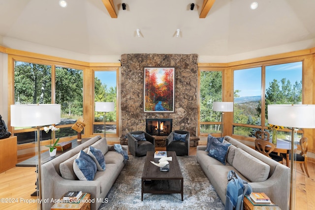 living room with a tiled fireplace, hardwood / wood-style flooring, beamed ceiling, and a high ceiling