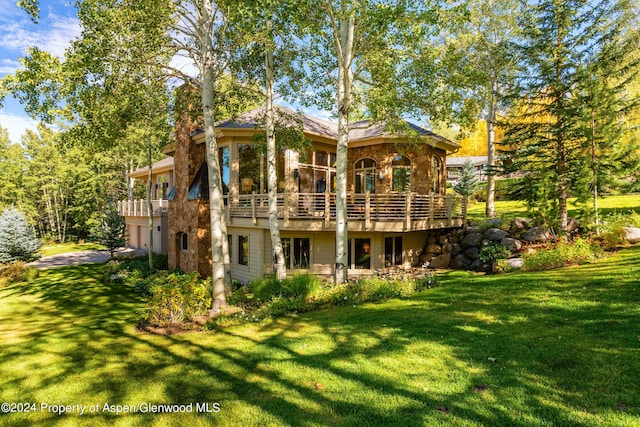 back of house featuring a lawn and a wooden deck