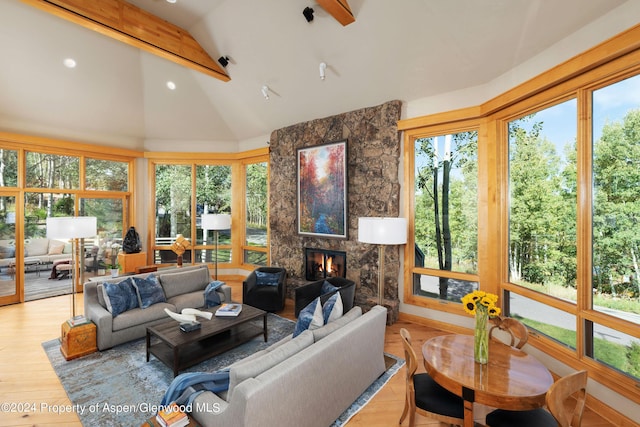 sunroom / solarium featuring a healthy amount of sunlight, a tiled fireplace, and vaulted ceiling