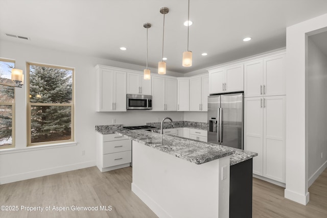 1 Eagle Claw Cir, Glenwood Springs, CO 81601 - kitchen with light stone counters, a kitchen island with sink, light wood-style floors, appliances with stainless steel finishes, and white cabinetry