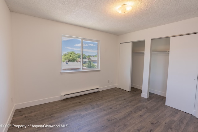 2655 Acacia Ave, Rifle, CO 81650 - unfurnished bedroom featuring a baseboard heating unit, two closets, dark wood-style floors, and a textured ceiling
