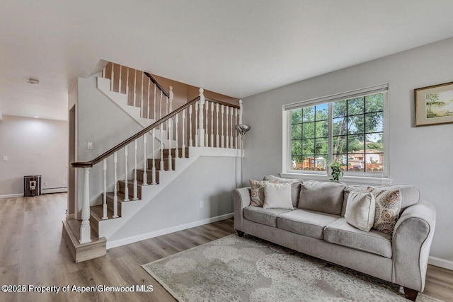 living area featuring stairway, baseboards, wood finished floors, and a baseboard radiator